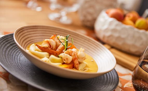 Fein angerichtete Meeresfrüchte auf Pasta in cremiger Sauce, dekoriert mit frischem Rosmarin, im Restaurant serviert