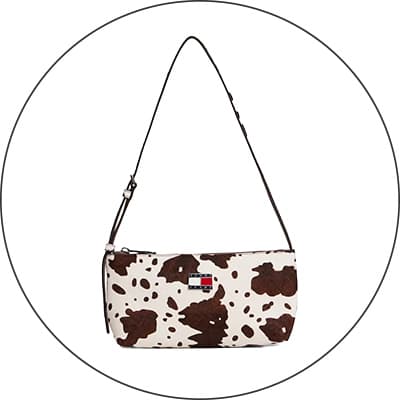 Kleine Schultertasche mit braun-weißem Fleckenmuster und rechteckigem Logo vorn, vor weißem Hintergrund