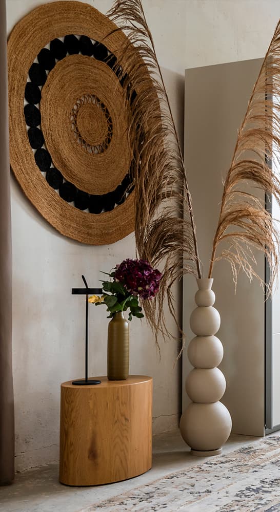 Schlafzimmer-Ecke mit dekorativem Wandteppich, Vase und Pflanzenarrangement.