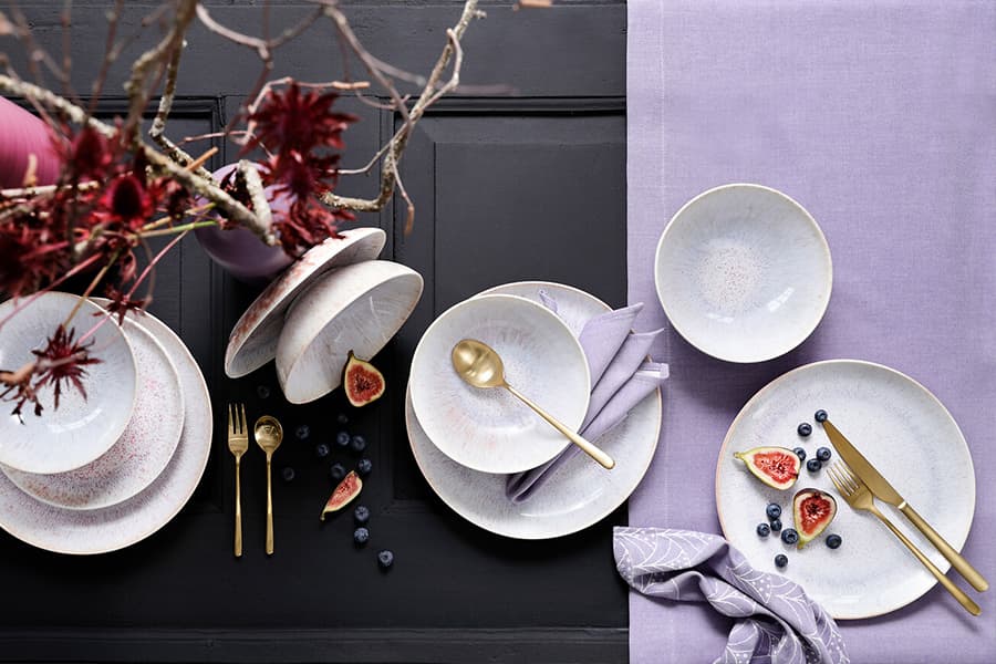 Moderner Waschtisch mit Naturstein-Waschbecken, Spiegel und bunten Handtüchern auf Regalen.