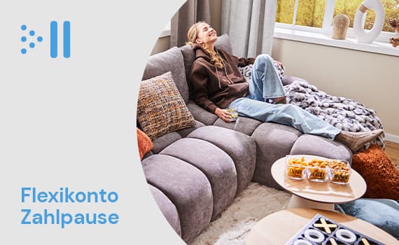 Flexikonto Zahlpause – Person in braunem Hoodie und blauer Jeans sitzt entspannt auf grauem Sofa mit Snacks auf dem Tisch.