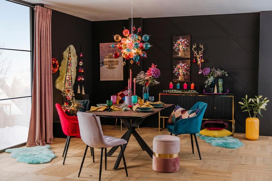 Bunt dekoriertes Esszimmer mit farbenfrohem Kronleuchter, blumenartigen Wandbildern und Tischgedeck mit Kerzen und Blumen.