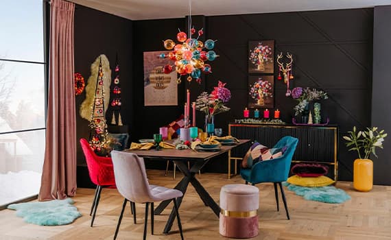 Bunter Essbereich mit stilvoller Dekoration, farbenfrohen Möbeln und festlichen Kerzen auf schwarzer Anrichte.