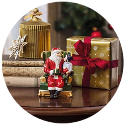 Weihnachtsdekoration – Keramikfigur von Weihnachtsmann mit Hund auf einem Tisch neben Geschenken und Büchern