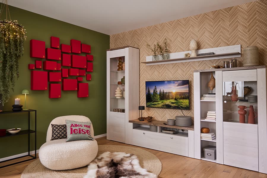 Alles auf leise – Modernes Wohnzimmer mit grünem Akzentwand, rotem Wanddeko, gemütlichem Sessel und TV-Schrankwand