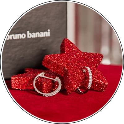 Bruno Banani – Zwei silberne Ringe vor glitzernden roten Sternen auf rotem Tuch