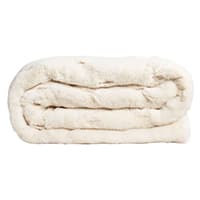 Gefaltete cremefarbene Decke, weich und flauschig, liegt auf einer weißen Fläche.