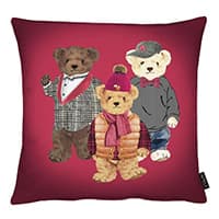Drei Teddybären in modischer Kleidung auf rotem Kissen, einer im Anzug, einer in Winterkleidung und einer in Freizeitkleidung