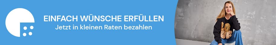 Einfach Wünsche erfüllen – Jetzt in kleinen Raten bezahlen. Frau in schwarzem Pullover mit Löwenmotiv und blauer Jeans sitzt auf einem Stuhl.
