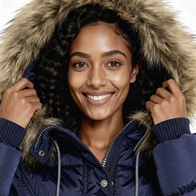 Frau in dunkelblauer Winterjacke mit Fellkapuze zieht die Kapuze enger.