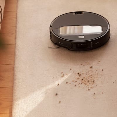 Roboterstaubsauger reinigt Teppich mit Krümeln, helle Umgebung.