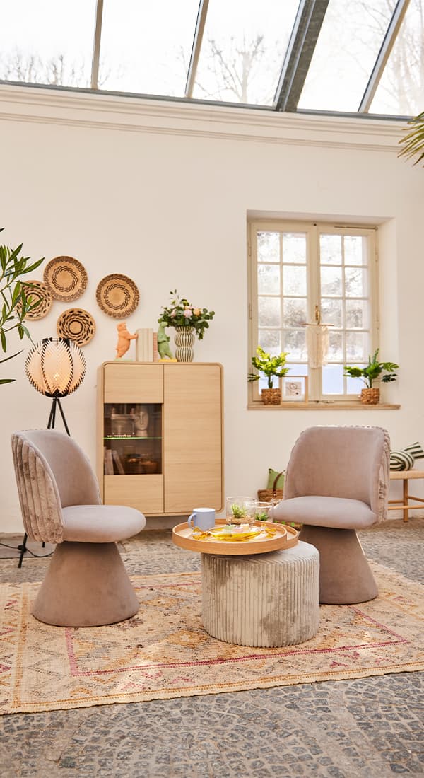 Gemütliche Sitzgruppe mit zwei Stühlen und einem kleinen Tisch, stilvoll dekoriert in einem hellen Raum mit Tageslicht.