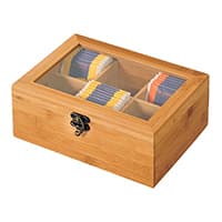 Teebox mit Glasdeckel und Metallschloss, gefüllt mit Teebeuteln in verschiedenen Farben