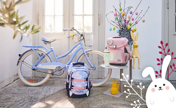 Osterdeko mit bunten Eiern, rosa Rucksack, Fahrrad und Hase – frühlingshafte Szene vor einer Tür