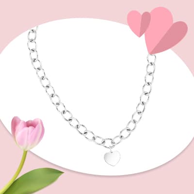 Halskette mit Gliederkette und Herzanhänger vor rosa Hintergrund mit Tulpe und Papierherzen