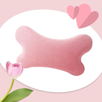 Rosa knochenförmiges Kissen vor hellem Hintergrund mit Tulpe und zwei rosa Herzen