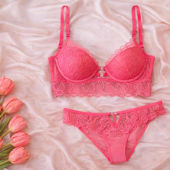 Rosa BH-Slip-Set mit Spitzenmuster liegt auf rosafarbenem Stoff, links daneben ein Strauß rosa Tulpen
