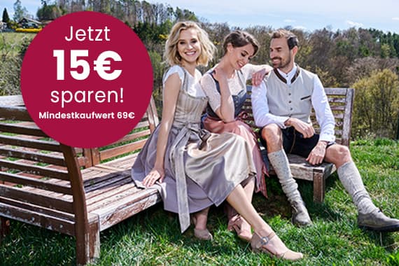 Jetzt 15€ sparen, Mindestkaufwert 69€ – drei Personen in Trachten sitzen auf Bänken im Grünen