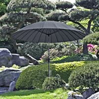 Dunkler Sonnenschirm im gepflegten Garten, umgeben von grünen Sträuchern, Bäumen und Felssteinen