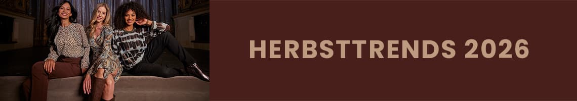 HERBSTTRENDS 2026 – drei Frauen sitzen nebeneinander auf einer Bank und präsentieren herbstliche Outfits