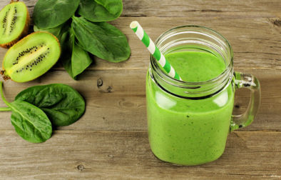 Healthy green smoothie with spinach and kiwi in a jar mug on wood, downward view