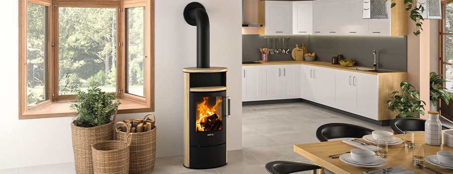 Moderne Küche mit Holzofen, brennendem Feuer, großen Fenstern und Tisch gedeckt für vier Personen